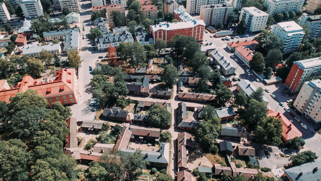 Ilmakuva vanhasta puutaloalueesta, jota ympyröi modernit kerrostalokorttelit.
